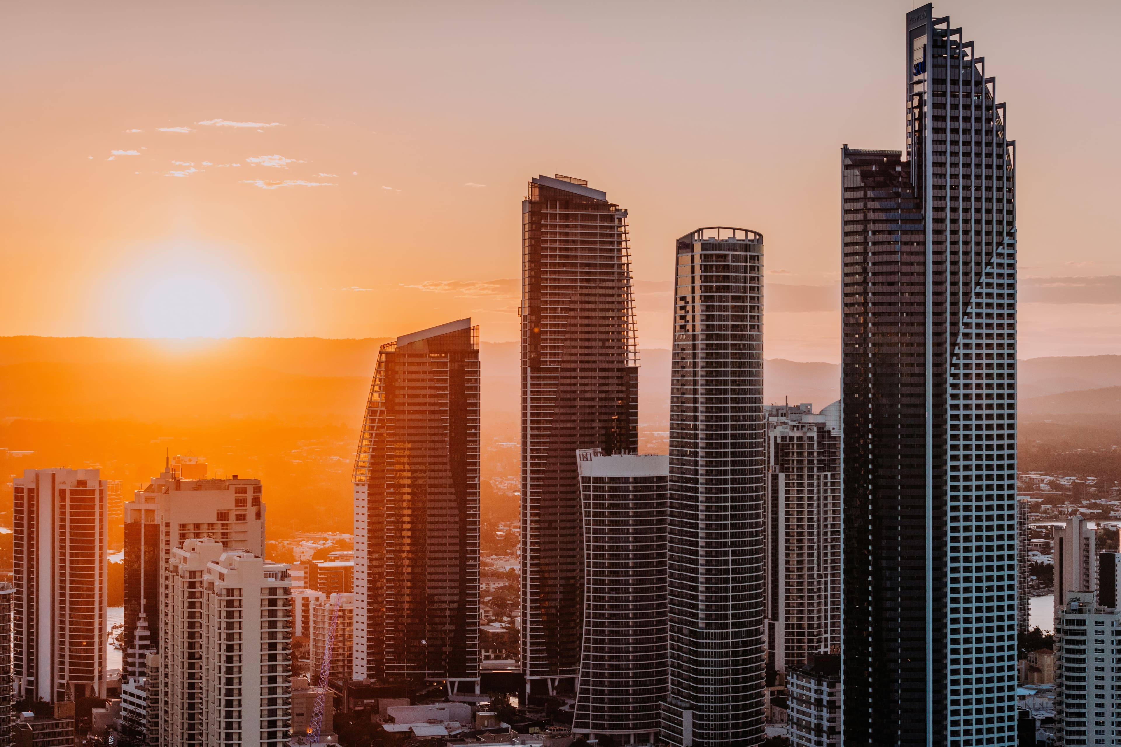 Sun setting through city skyline buildings.