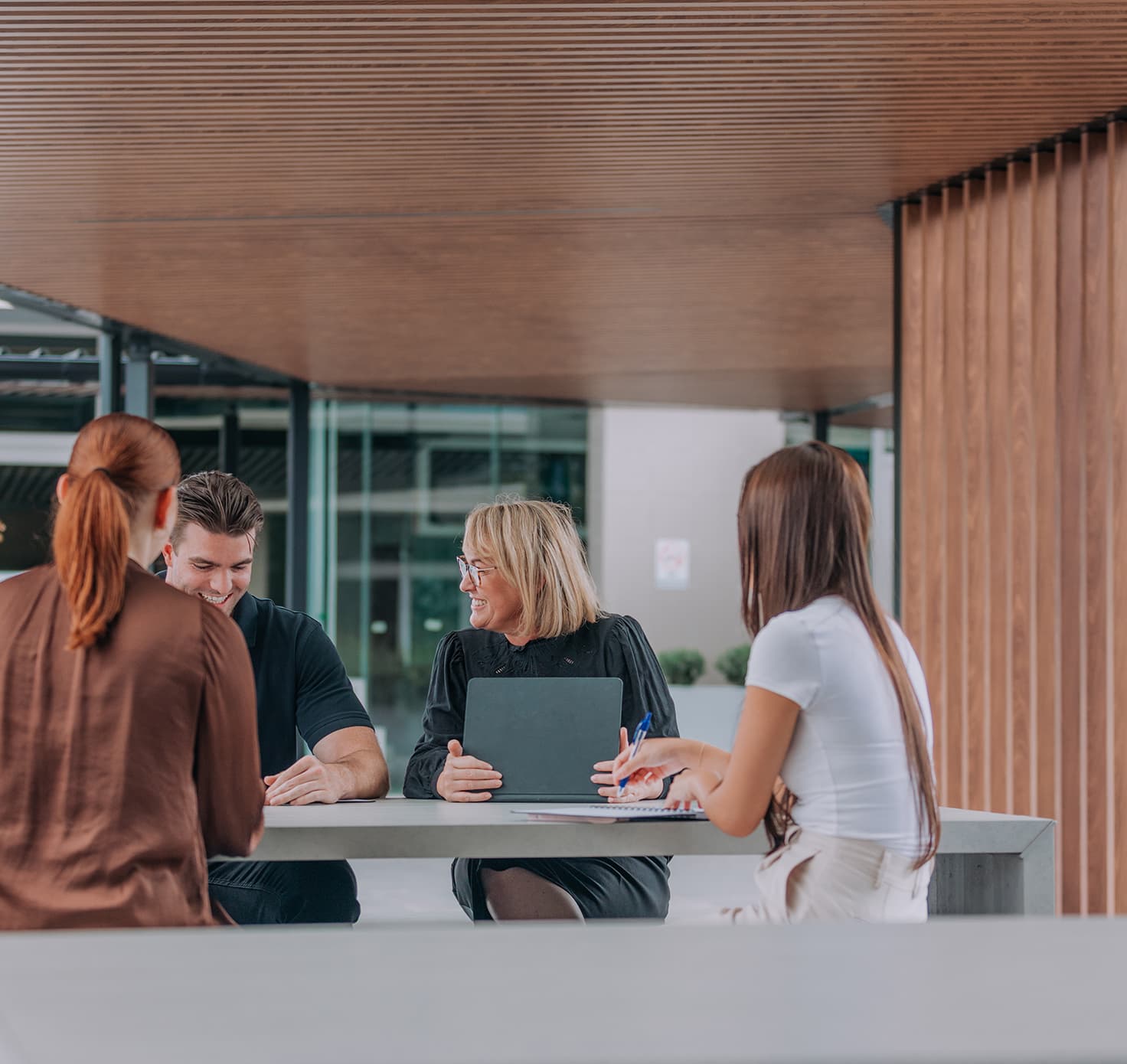 Professional people sit at a table outside in conversation.